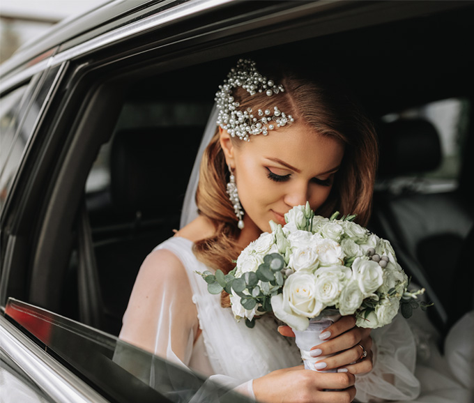 Bride sitting in a limo looking at her bouquet.